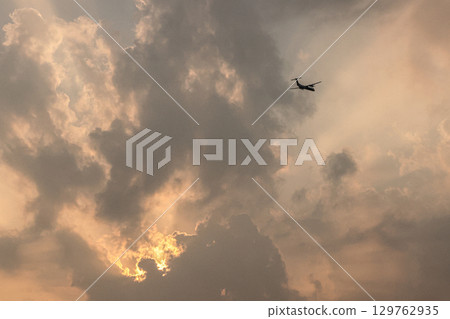 Airplane flying in the sunset sky 129762935