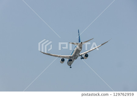 A passenger plane flying under a clear blue sky A passenger plane flying under a clear blue sky 129762959