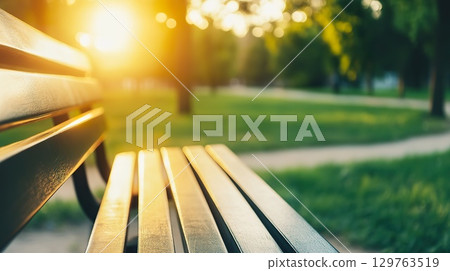 Empty Park Bench Bathed in Golden Sunlight During Sunset. 129763519