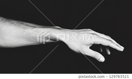Human hand and arm reaching out in dark monochrome setting. 129763521