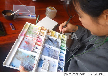 Young teenager using watercolour for painting as hobby. Young teenager using watercolour for painting as hobby. 129763910
