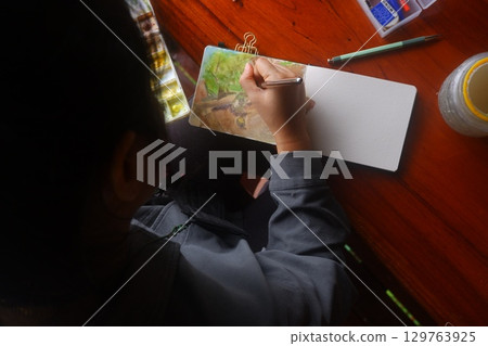 Young teenager using watercolour for painting as hobby. 129763925