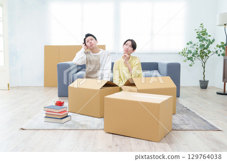 A couple sorting cardboard boxes with troubled expressions A couple sorting cardboard boxes with troubled expressions 129764038