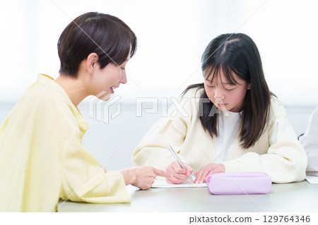 A girl studying, her mother teaching her A girl studying, her mother teaching her 129764346