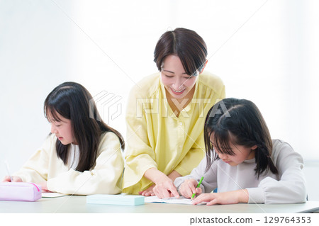 A girl studying, her mother teaching her 129764353