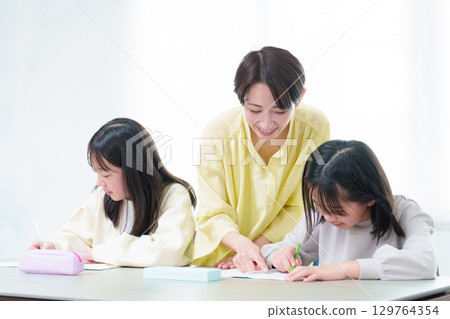 A girl studying, her mother teaching her 129764354