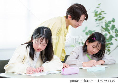 A girl studying, her mother teaching her A girl studying, her mother teaching her 129764359