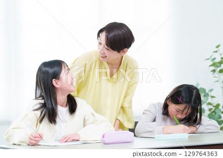A girl studying, her mother teaching her A girl studying, her mother teaching her 129764363