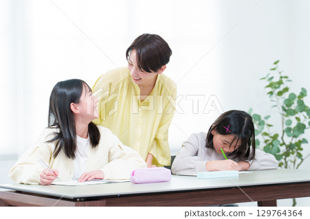 A girl studying, her mother teaching her 129764364