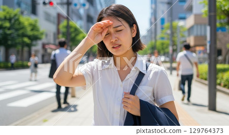 A woman wiping away sweat in the intense heat 129764373