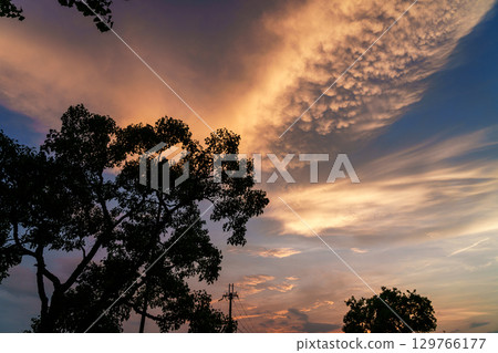 Sunset sky over the city: Majestic, scaly golden clouds appearing above a park in a residential area after sunset ② 129766177