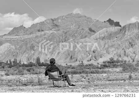 asian man sitting in a chair looking at a mountain asian man sitting in a chair looking at a mountain 129766231