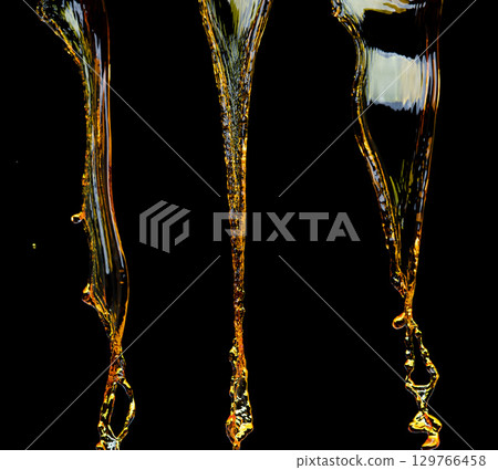 Orange, lemon juice or oil lubricant splash, liquid gold yellow drink drops. Fruit beverage water elements in line form . Fresh splashing and flowing jets, black background isolated freeze motion 129766458