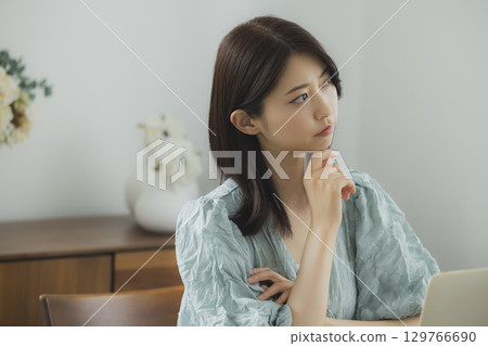 A woman watching a computer in a room 129766690