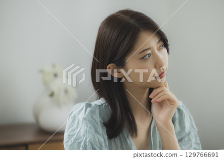 A woman watching a computer in a room 129766691