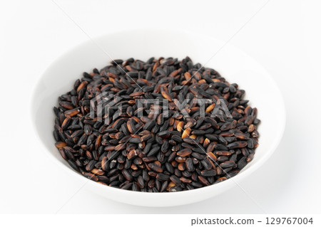 Black rice in a plate on a white background 129767004