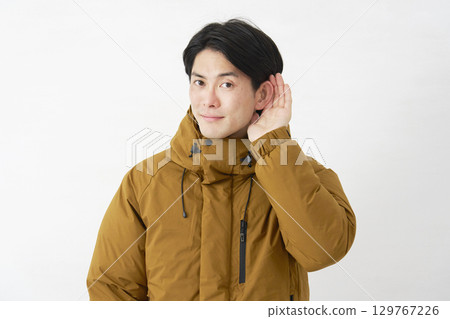 一位身穿羽絨外套的男子在白色背景上認真聆聽 129767226