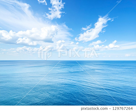 Blue waves reflect the summer sunlight, painting a serene seascape where the ocean meets the horizon under a vast, cloudy sky 129767264