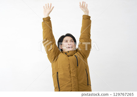 Man wearing down jacket stretching white background 129767265