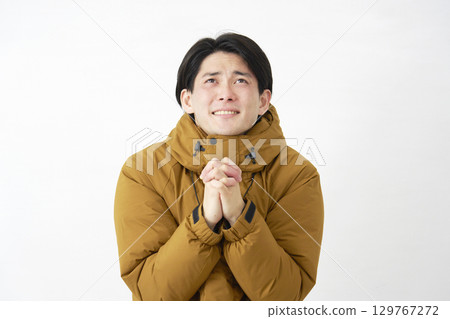 Man wearing down jacket pleading white background 129767272