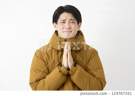 A man wearing a down jacket makes a request on a white background 129767281