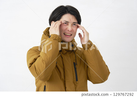 Man wearing down jacket, headache, white background 129767292
