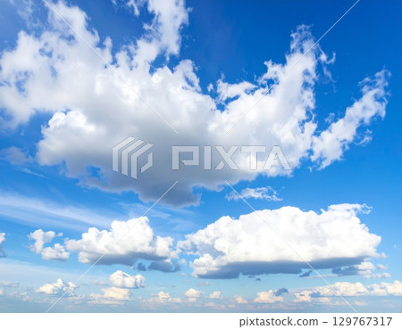 Beautiful and fluffy white clouds float in the vast blue summer sky Beautiful and fluffy white clouds float in the vast blue summer sky 129767317