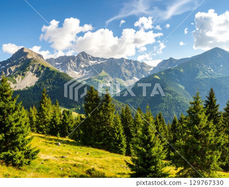 Alpine summer landscape with green valleys, snow-capped peaks, and a clear blue sky 129767330