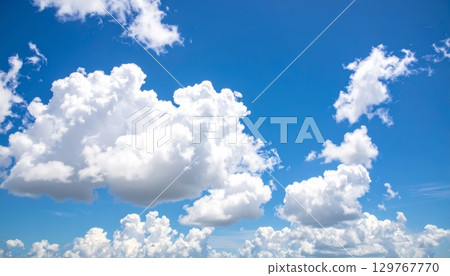 Beautiful blue sky and clouds hover over a vast green meadow, creating a peaceful country landscape on a warm summer day 129767770