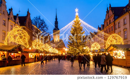 A stunning Christmas tree glows at night in Bangkok, casting a festive light on the ancient Thai architecture of a nearby temple 129767919