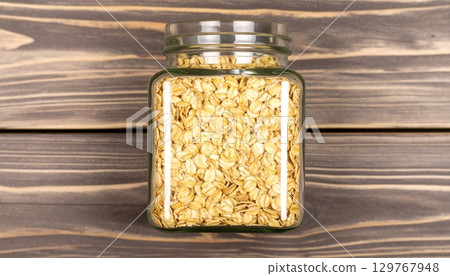 Dry raw organic oatmeal and buckwheat cereal grains in glass jars on a white background 129767948