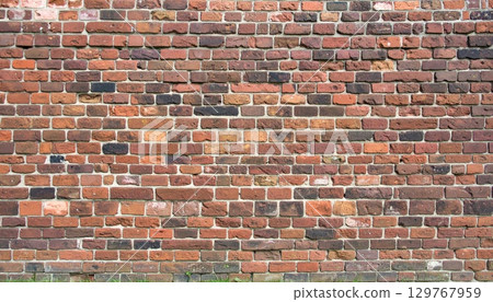 An old red brick wall with a textured pattern of cement and stone blocks 129767959