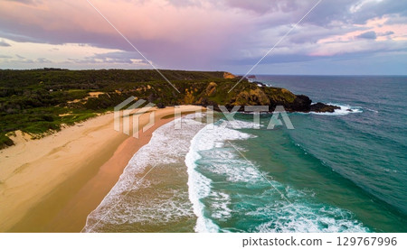 Vibrant summer sunset over the tropical coast with waves washing the sandy shore Vibrant summer sunset over the tropical coast with waves washing the sandy shore 129767996
