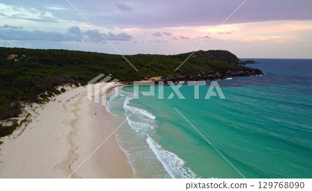 Vibrant summer sunset over the tropical coast with waves washing the sandy shore 129768090