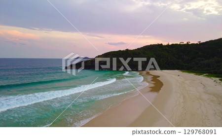 Vibrant summer sunset over the tropical coast with waves washing the sandy shore Vibrant summer sunset over the tropical coast with waves washing the sandy shore 129768091