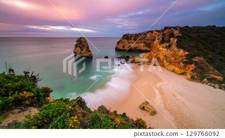 Vibrant summer sunset over the tropical coast with waves washing the sandy shore 129768092
