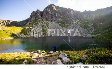 Autumn landscape with a tranquil mountain lake reflecting the surrounding peaks, a forest, and a clear sky Autumn landscape with a tranquil mountain lake reflecting the surrounding peaks, a forest, and a clear sky 129768100