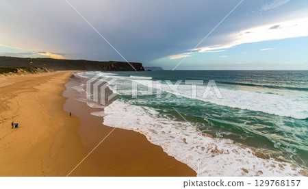 Sunrise over a tropical beach with golden sand and gentle waves on the horizon Sunrise over a tropical beach with golden sand and gentle waves on the horizon 129768157