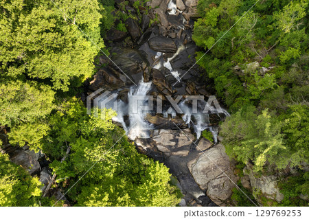 Beautiful landscape of high waterfall with falling down clear water from rocky boulders between green lush woods. Whitewater Falls in Nantahala National Forest, North Carolina, USA 129769253