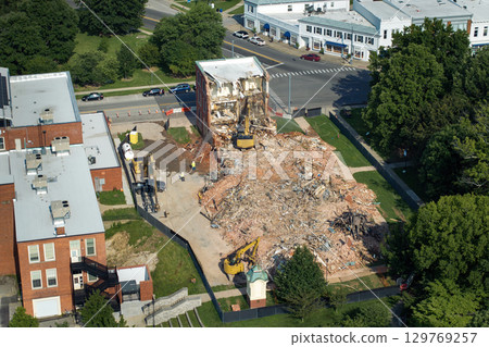 Old building demolition site. Construction excavator tearing down obsolete brick walls of Historic Edwards Building in Berea, Kentucky, USA. City planning concept 129769257