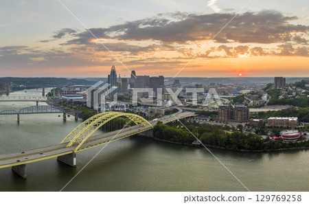 Downtown district of Cincinnati city in Ohio, USA at sunset with driving cars traffic on Daniel Carter Beard Bridge and brightly illuminated high skyscraper buildings. American travel destination 129769258