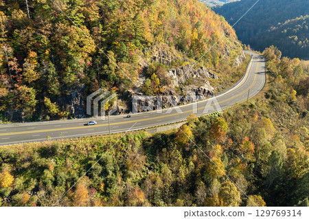 Freeway road with fast moving traffic cars and trucks in North Carolina Appalachian mountains in fall season. Interstate transportation infrastructure in USA Freeway road with fast moving traffic cars and trucks in North Carolina Appalachian mountains in fall season. Interstate transportation infrastructure in USA 129769314