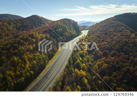 Aerial view of empty I-40 freeway in North Carolina leading to Asheville through Appalachian mountains in golden fall season. Energy crisis and high gas prices concept 129769346