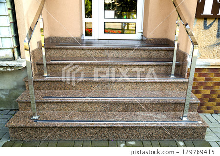 Detail of a house facade. New granite stairs with metal railings. 129769415