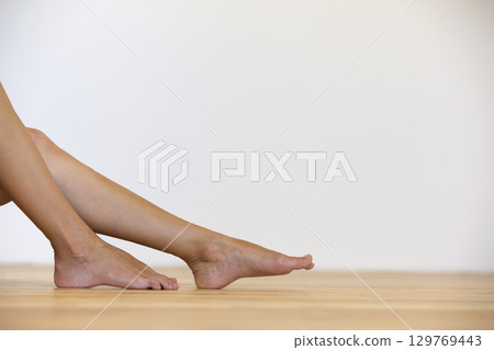 Woman bare feet on the floor. Legs care and skin treatment concept. Woman bare feet on the floor. Legs care and skin treatment concept. 129769443
