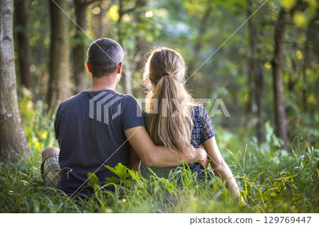 Youg couple, man and a woman sitting together outdoors enjoying nature. 129769447