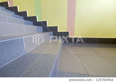 Wide staicase covered with ceramic tiles indoors in a house interior. 129769468