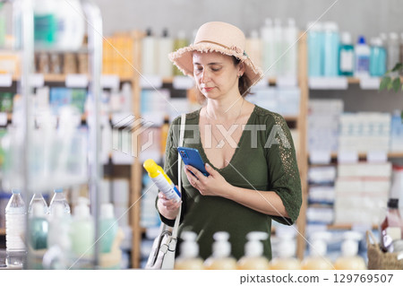 Woman in pharmacy scans QR code on mosquito repellent Woman in pharmacy scans QR code on mosquito repellent 129769507