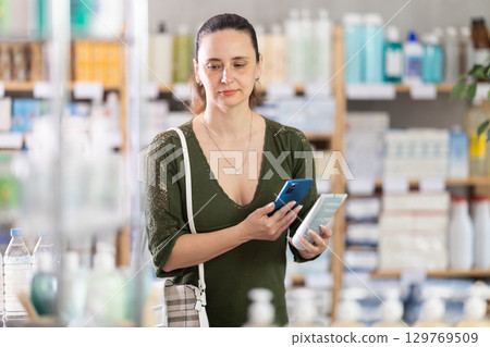 Woman scans on mobile qr code cream in pharmacy 129769509