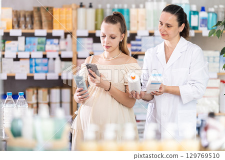 Pregnant woman buyer scans cream qr code with woman pharmacist 129769510